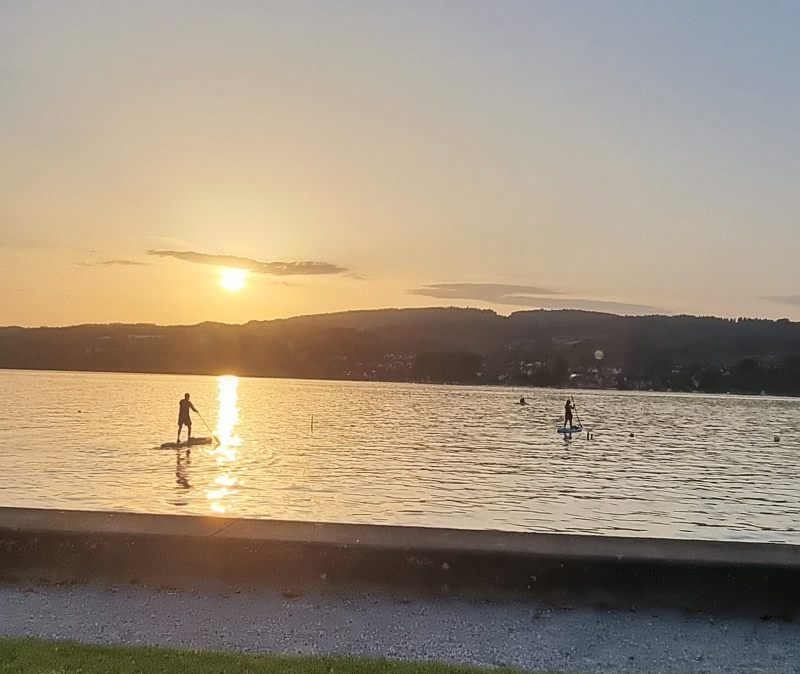 Sonnenuntergang mit Stand-Up-Paddlern am See